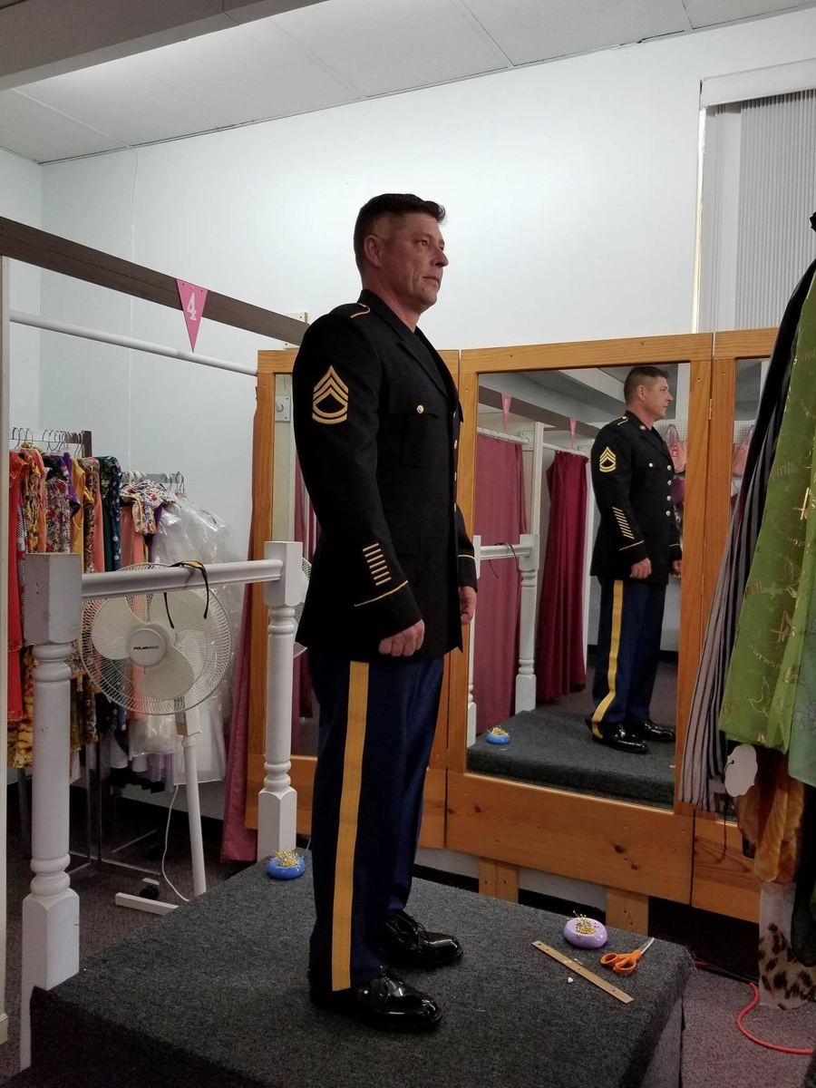 A customer in a fitted Army dress uniform on the fitting platform at Golden Needle